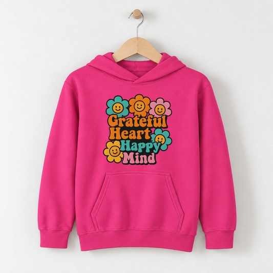 Grateful Heart, Happy Mind – Kids Classic Hoodie Sweatshirt on a wooden hanger and wall peg, with a naturally collapsed hood