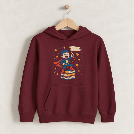 Cute Bookworm Superhero – Kids Classic Hoodie Sweatshirt on a wooden hanger and wall peg, with a naturally collapsed hood