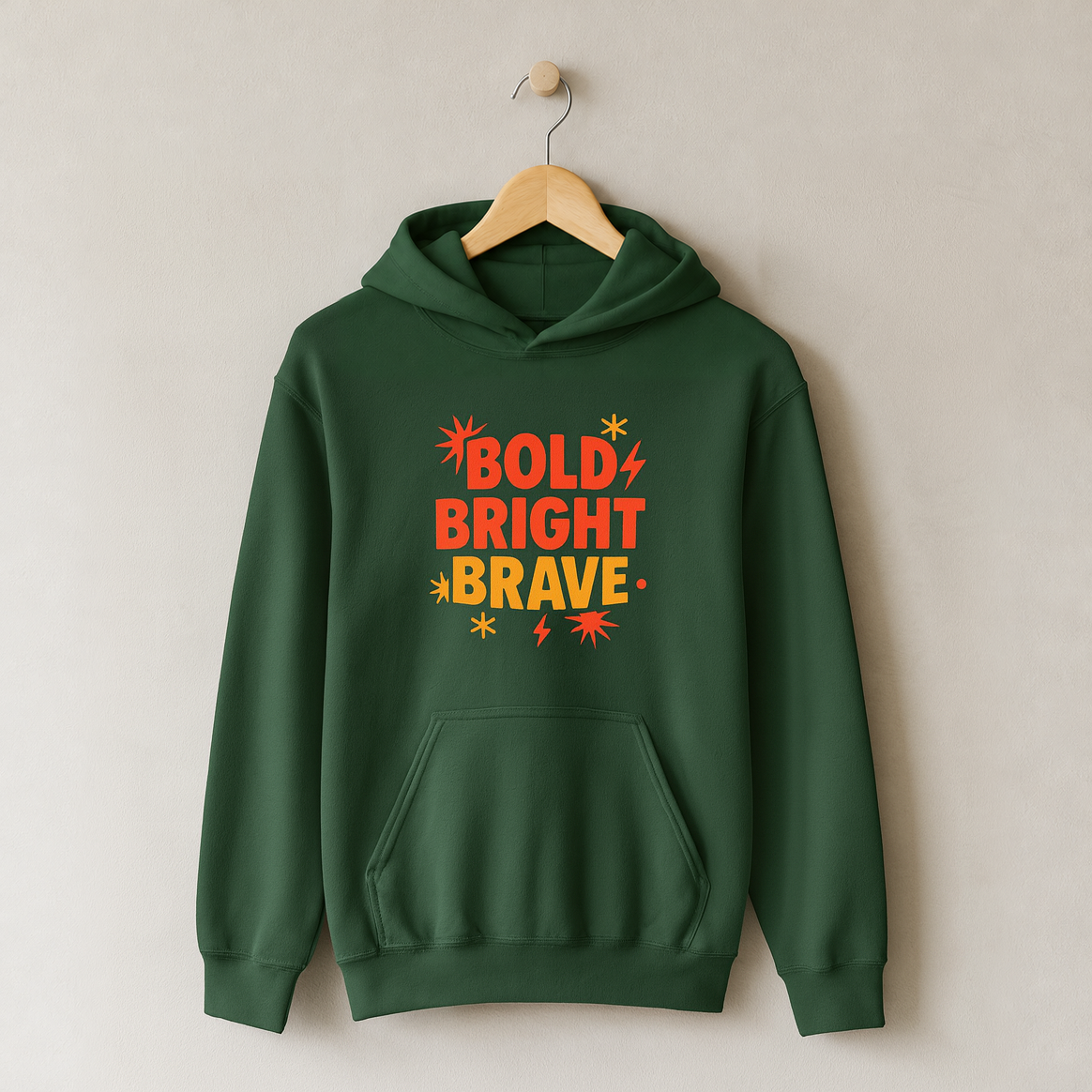 Bold Bright Brave – Kids Classic Hoodie Sweatshirt on a wooden hanger and wall peg, with a naturally collapsed hood